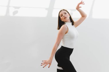 Parlak bir stüdyoda modern dans gösterisi yapan zarif bir dansçı. Yeteneğini ve hareket tutkusunu sergiliyor.