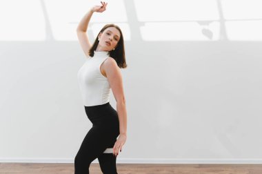 Parlak bir stüdyoda modern dans figürleri sergileyen zarif bir dansçı. Esneklik ve sanatsal ifade sergiliyor.