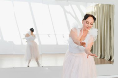 Zarif balerin, parlak bir stüdyoda bale hareketleri yapıyor altın yıllarında dans için zarafet ve tutku sergiliyor.