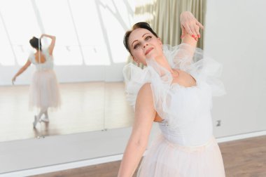 Yaşlı balerin, dans stüdyosunda beyaz bir bale elbisesiyle zarif bir şekilde dans eder. Tutkusunu ve kendini baleye adadığını gösterir.