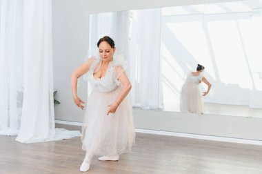 Zarif balerin dans stüdyosunda bale adımları çalışıyor. Yansıması zarif hareketlerini yansıtıyor.