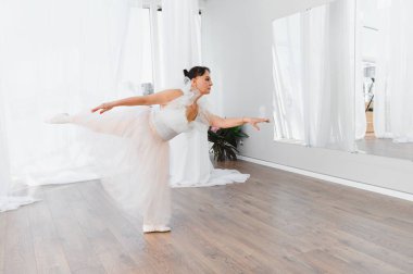 Olgun balerin bir dans stüdyosunda bale çalışıyor. Hareketlerinde zarafet ve duruş sergiliyor.