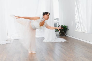 Yaşlı balerin dans stüdyosunda kolunu ve bacağını nazikçe uzatıyor. Tutkusunu ve kendini baleye adadığını gösteriyor.