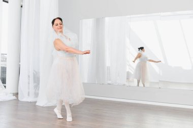 Yaşlı balerin, parlak bir stüdyoda zarif bir şekilde dans eder. Tutkusunu ve kendini baleye adadığını gösterir.