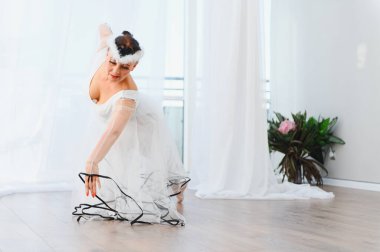 Yaşlı balerin beyaz bir elbiseyle zarif bir şekilde dans ediyor, parlak bir stüdyoda zarafet ve tutku sergiliyor.