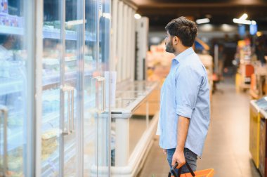 Marketteki dondurulmuş yiyecekleri seçen genç Hintli bir adam.