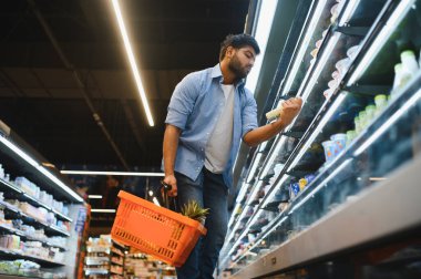 Süpermarket buzdolabı koridorunda sebze seçerken odaklanmış müşteri okuma bilgileri
