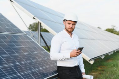 Güneş panellerini kontrol eden mühendis yenilenebilir enerji üretimini ve güneş çiftliğindeki sürdürülebilir teknoloji gelişimini izliyor.
