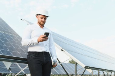 Telefondaki verileri kontrol eden, güneş enerjisi santralindeki yenilenebilir enerji üretimini denetleyen bir mühendis.