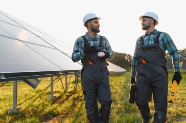 Güneş panellerini tartışan ve denetleyen iki işçi yenilenebilir enerji tesisinde optimal performans sağlıyorlar.