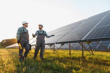 İki mühendis, sürdürülebilir yeşil enerji çözümleri geliştirerek, büyük ölçekli bir güneş enerjisi kurulumu için bakım planlarını tartışıyor.