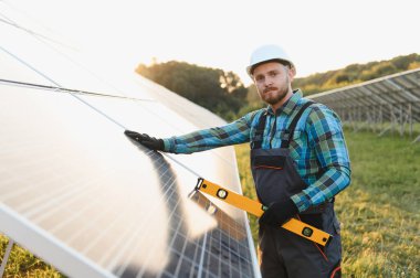 Genç adam fotovoltaik paneller kurup sürdürüyor, temiz enerji ve çevresel sürdürülebilirliğe katkıda bulunuyor