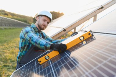 Uygun hizalama ve verimliliği sağlamak için bir seviye aracı kullanarak, bir alana güneş panelleri kuran mühendis