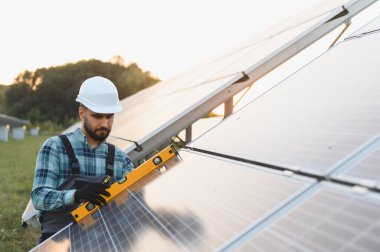 İşçi güneş enerjisi sistemleri kuruyor, verimlilik için fotovoltaik panellerin düzgün hizalanmasını sağlıyor. Yenilenebilir enerji kavramı