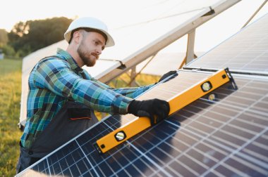 Güneş panelleri kuran mühendis, sürdürülebilir yeşil enerji üretmek için uygun hizayı sağlıyor