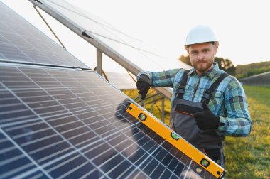 Adam yenilenebilir enerji üretimi için güneş panelleri kuruyor, ruhsal seviyeye uygun hizayı sağlıyor ve onaylama gösteriyor