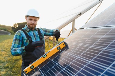 Güneş paneli teknisyeni ruh seviyesini kullanarak kurulumu kontrol ediyor, yeşil enerji ve sürdürülebilirliği destekliyor