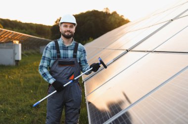 Kasketli ve tulumlu gülümseyen işçiler, bir cam sileceği, bir güneş çiftliğinde durup, temiz verimlilik sağlıyorlar.