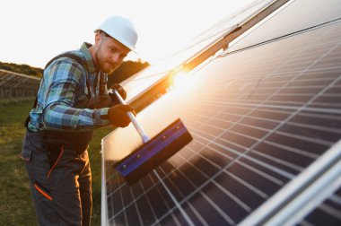 Günbatımında güneş panelinde bakım yapan işçiler, sürdürülebilir enerji ve verimliliği teşvik ediyorlar.