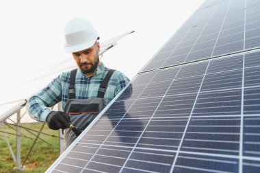Başlık ve tulum takan mühendis, sürdürülebilir temiz enerji üretimi için güneş paneli sistemi kuruyor
