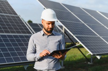 Başlık takan mühendis, güneş enerjisi santralinde tablet kullanıyor. Sürdürülebilir teknoloji geliştirmeye odaklanmak