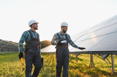 İki işçi fotovoltaik hücrelerin montajını tartışıyor, yeşil enerji üretimini güvence altına alıyorlar.