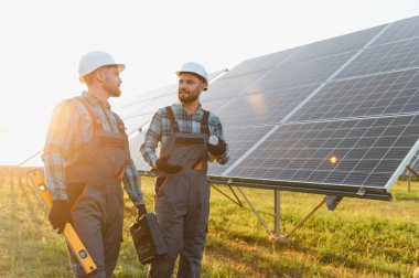 İki mühendis büyük bir güneş enerjisi santralinde yenilenebilir güneş enerjisini tartışıyorlar.