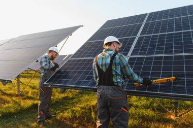 Fotovoltaik paneller kuran güneş enerjisi santrali işçileri, verimli yenilenebilir enerji üretimi için uygun hizalamayı sağlıyorlar