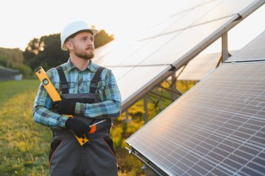 Çalışanlar güneş panellerini kontrol ediyor, verimli bir yenilenebilir enerji üretimi sağlıyor. Yeşil teknoloji ve sürdürülebilir güç
