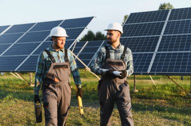 İki mühendis, güneş paneli alanında yenilenebilir enerji gelişimine odaklanarak planlarını tartışıyorlar.