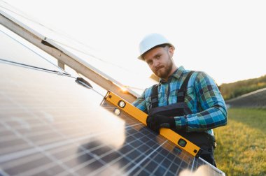 Güneş panelinde ruh seviyesini kullanan teknisyen yeşil alanda maksimum enerji emilimi için doğru açıyı sağlıyor.