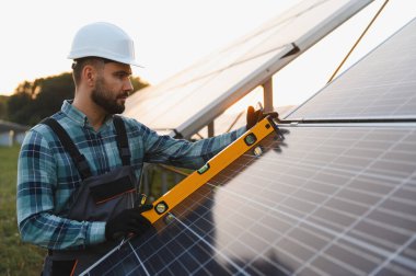 Güneş panelleri kuran mühendis, sürdürülebilir ve yenilenebilir enerjiyi destekleyen, bir seviye aracı ile hassas hizalama