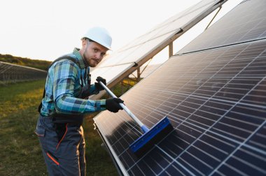 Bir enerji santralinde enerji verimliliğini koruyan güneş paneli temizleme ekipmanı işçisi