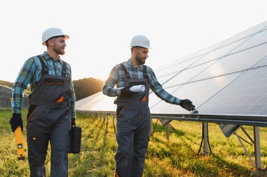Güneş panellerini gün batımında yeşil enerji alanında inceleyen iki mühendis.