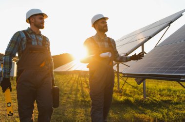 Güneş enerjisi panellerini güneş çiftliğine kuran iki işçi sürdürülebilir bir çevrede temiz elektrik üretiyor.