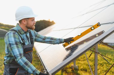 Bir güneş çiftliğindeki fotovoltaik panellerin hizalanmasını kontrol eden işçiler, yenilenebilir enerji üretimi için hassas bir kurulum sağlıyorlar