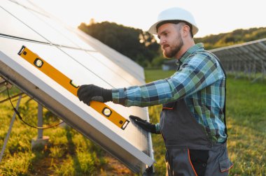 Sürdürülebilir enerji odaklı bir alanda kurulum sırasında bir güneş panelinin seviyesini kontrol eden mühendis veya teknisyen