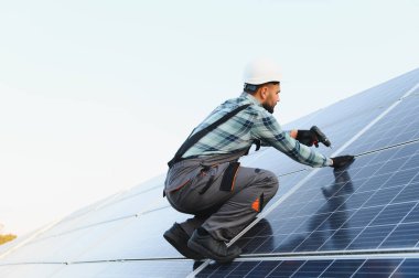 Erkek teknisyen çatıya fotovoltaik güneş panelleri kurarak yenilenebilir elektrik üretiyor. Sürdürülebilir enerji kavramı