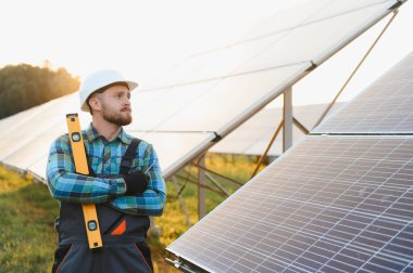Güneşli bir alanda güneş panellerini inceleyen erkek mühendis verimli bir yenilenebilir enerji üretimi ve sürdürülebilir enerji altyapısı sağlıyor