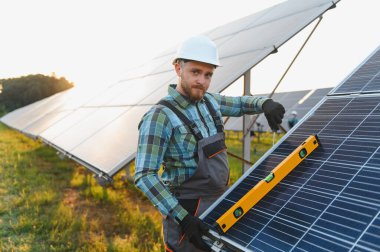 Bir güneş paneli kuran teknisyen, kesin hizalama için bir seviye kullanarak, yeşil enerji üretimine ve sürdürülebilirliğe katkıda bulunur