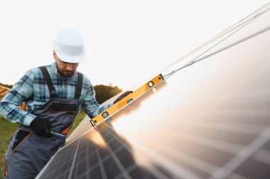 Güneş paneli kurulumu sırasında bir seviye kullanan işçiler, sürdürülebilir enerji üretimi için hassasiyete odaklanırlar