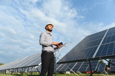 Bir fotovoltaik enerji santralinde güneş enerjisi üretimini doğrulayan mühendis, sürdürülebilirlik ve yeşil teknolojiye odaklanıyor