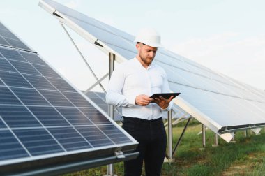 Kask takan adam tablet üzerinde güneş enerjisi performansını kontrol ediyor, sürdürülebilir enerji ve yeşil teknolojiyi teşvik ediyor.