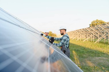 Güneş panellerini kırsal bir güneş çiftliğine kuran mühendisler, teknisyenler parlak gökyüzü altında sürdürülebilir temiz enerji altyapısı inşa ediyorlar