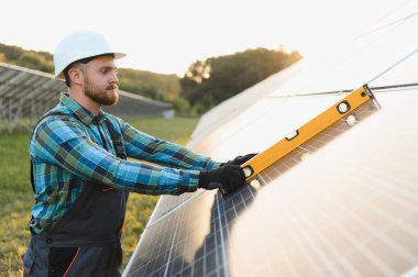 Güneş panelini ruhsal seviyede eğip yenilenebilir enerji üretimi için ideal konumlandırmayı sağlayan işçiler