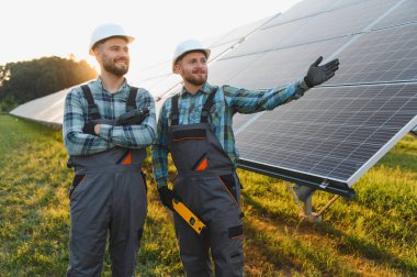 Güneş panellerinin montajını tartışan, yenilenebilir yeşil enerjiyi destekleyen iki işçi.