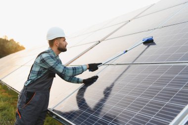 Bir güneş paneli alanında bakım yapan işçiler, verimliliği sağlarlar ve sürdürülebilir enerji üretimine katkıda bulunurlar