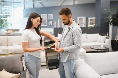 Yeni ev eşyaları için döşeme malzemesi seçen genç bir çift modern bir galeride karar veriyorlar.