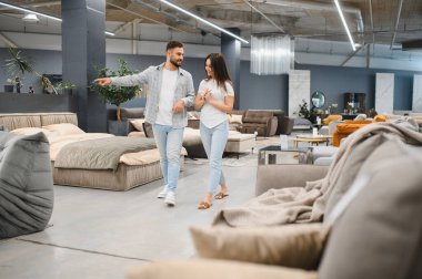 Genç bir çift çağdaş bir galeride ev mobilyalarını tartışıyor. Yeni bir ev dekorasyonu planlıyorlar.