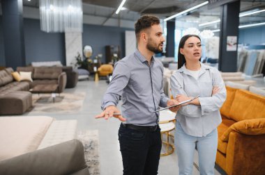 Sales consultant assisting a client in a modern furniture showroom, discussing products and helping with purchasing decisions